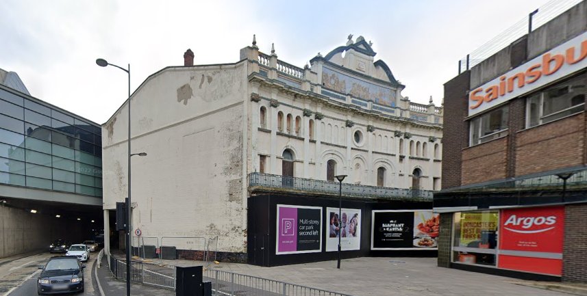 A Google Streetview image showing the Grand Theatre, Doncaster stuck between a major road and a shopping centre, and closed and boarded up in November 2022 - Click to interact.